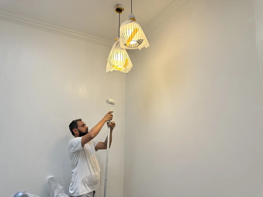 Painter rolling ceiling white paint, HDB Singapore service